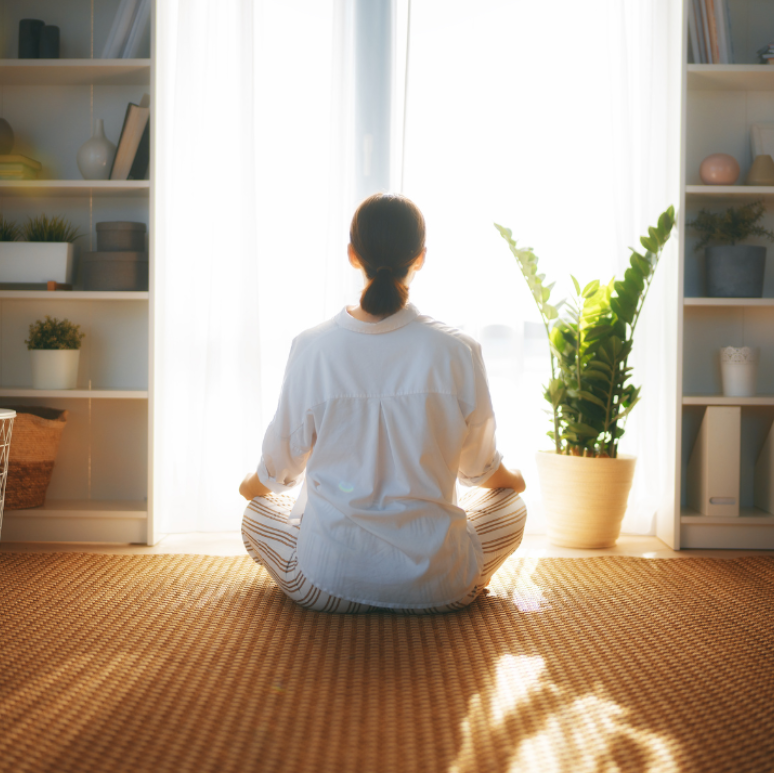 Woman practicing mindfulness at home, sitting in sunlight—symbolizing healing and understanding shame from trauma.